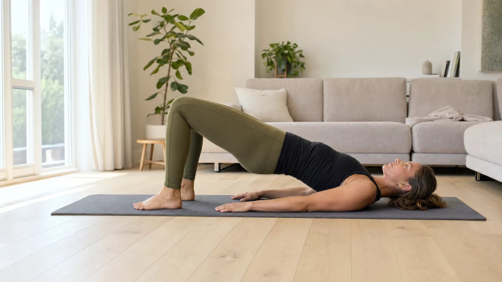 Volwassen vrouw doet thuis een glute bridge op een mat voor bilspieren trainen thuis.