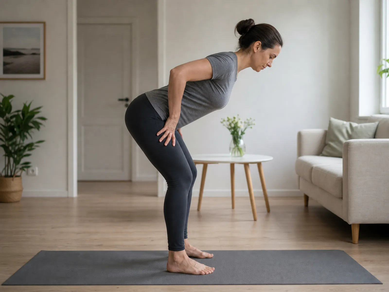 Adult woman practises a hip hinge at home with a neutral spine.