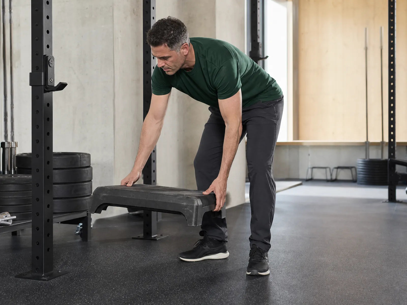 Erwachsener Fitnessstudiobetreiber räumt eine Bodenfläche für eine Nordic-Curl-Station im Fitnessstudio frei.
